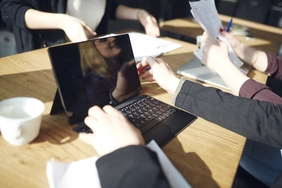Studentin sitzt vor einem Laptop, ihr Gesicht spiegelt sich im Gerät