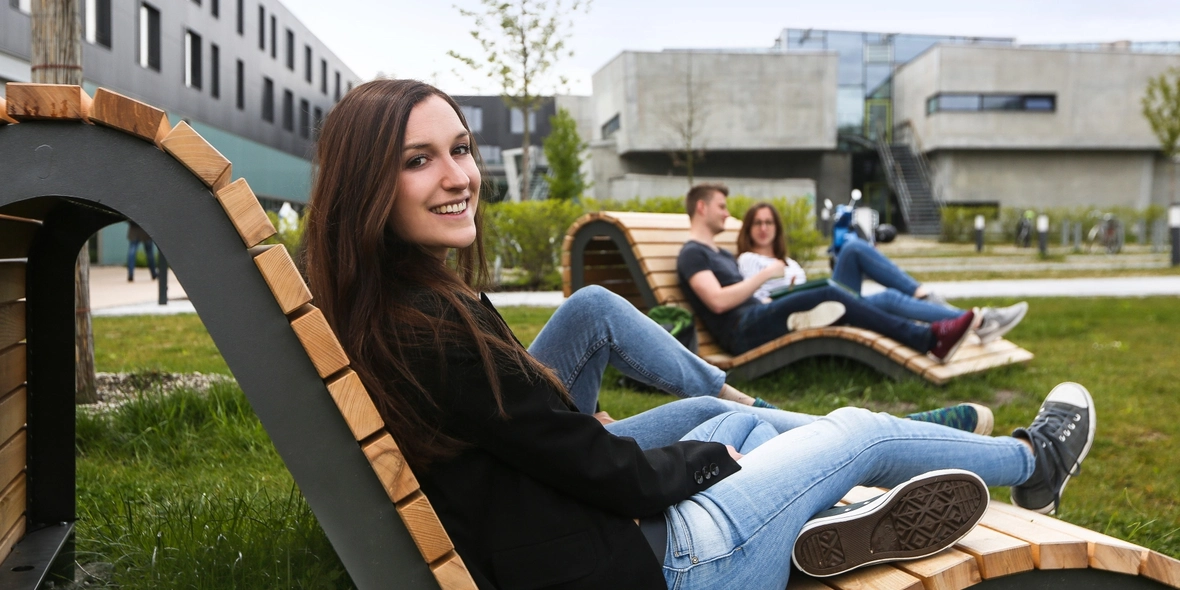 Studierende auf Holzliege auf Campuswiese