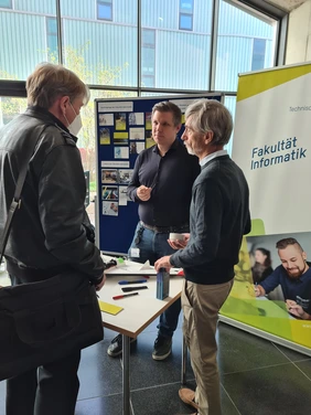 Professors Jarschel and Gold talking to a teacher at the Faculty of Computer Science´s stand