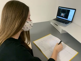 Studentin sitzt vor Laptop bei einer Videokonferenz