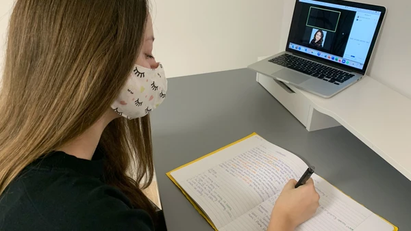 Studentin sitzt vor Laptop bei einer Videokonferenz