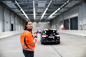 Junge Frau steht in einer Halle für Fahrzeugtests