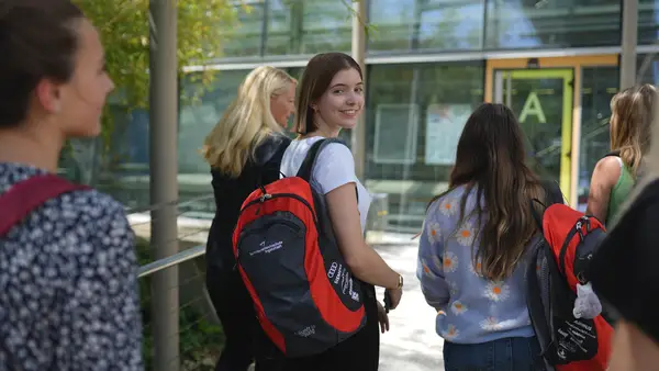 Studentin auf dem Weg Richtung THI Gebäude. Sie lächelt in die Kamera.