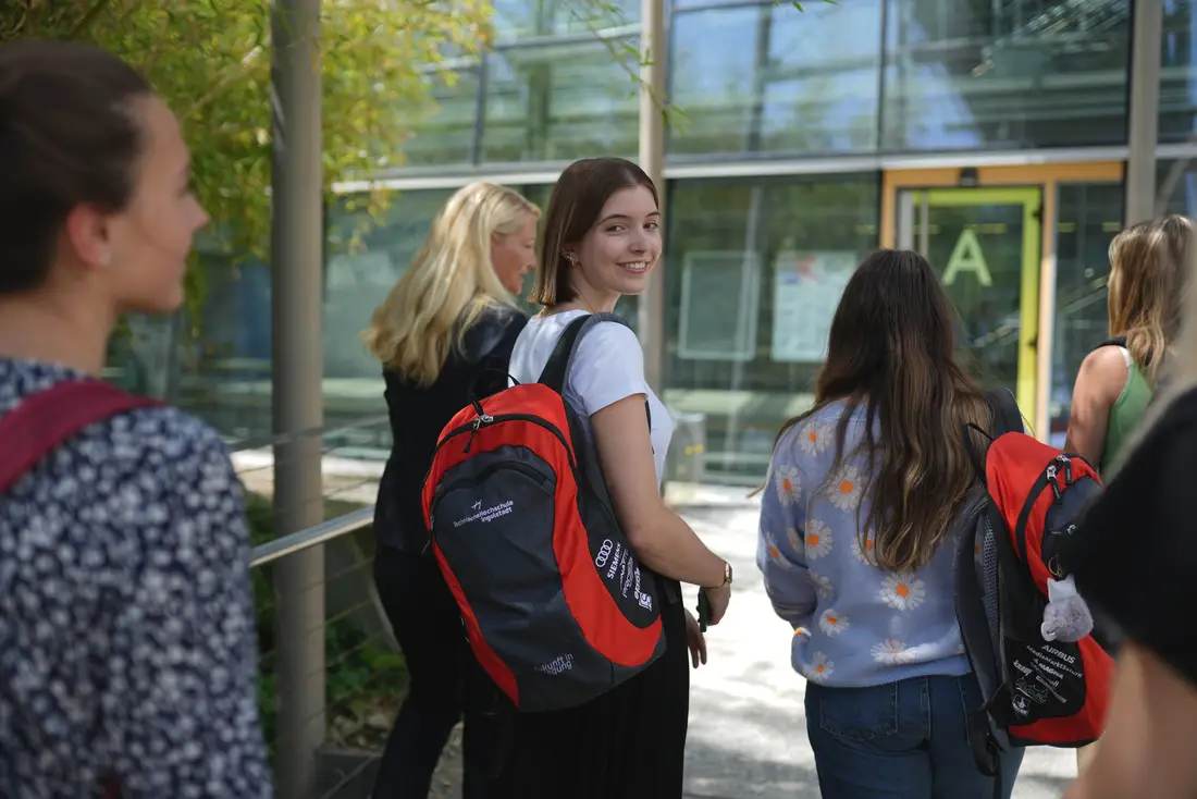 Studentin auf dem Weg Richtung THI Gebäude. Sie lächelt in die Kamera.