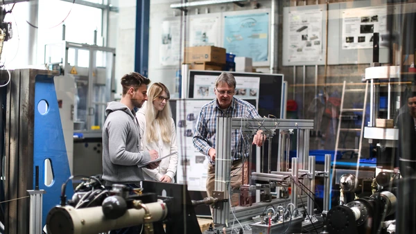 Professor mit zwei Studenten im Maschinenbau-Labor